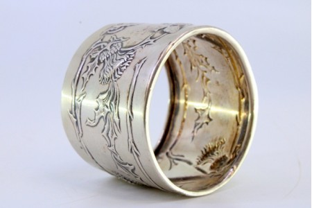 Argola de guardanapo em prata com frutos, ramos e flores relevadas envolvendo cartelapara monograma.